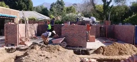 Team working along the foundation brickwork of a new build