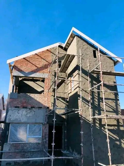 Double-storey home under construction with scaffolding and fresh plaster