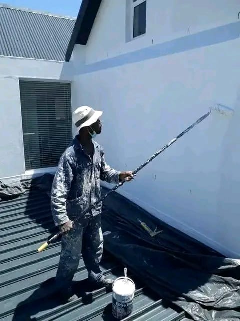 Painter rolling coating onto a metal roof