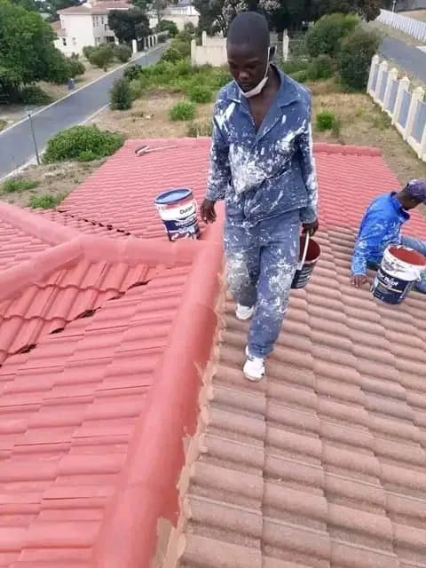 Roofing team moving paint across a tiled roof